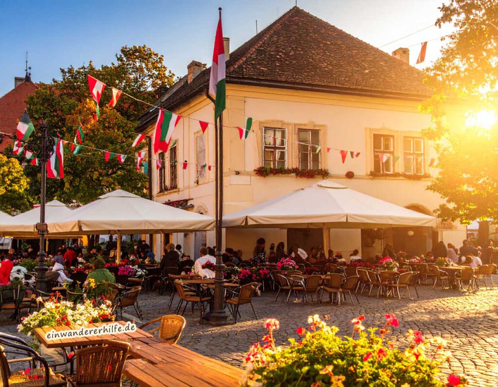 Belebter Marktplatz in Ungarn mit Cafés und historischer Architektur. Auswandern nach Ungarn leicht gemacht – Ratgeber von Marion Schanne.